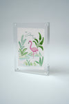 Framed Colony Hotel flamingo painting standing upright against a light background