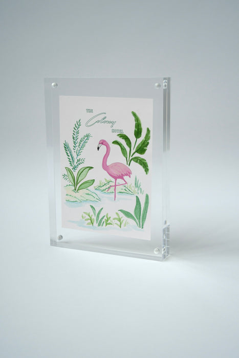 Framed Colony Hotel flamingo painting standing upright against a light background